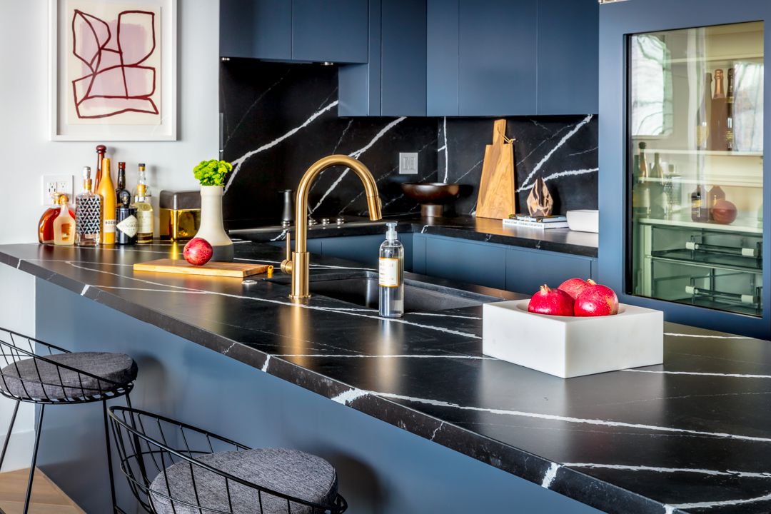 مطبخ باللونين الأسود والأزرق مع أسطح تشبه الرخام الأسود.