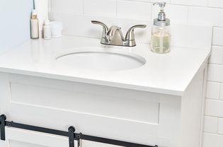 منضدة الحمام المثبتة حديثًا مع سطح عمل أبيض ومغسلة واحدة