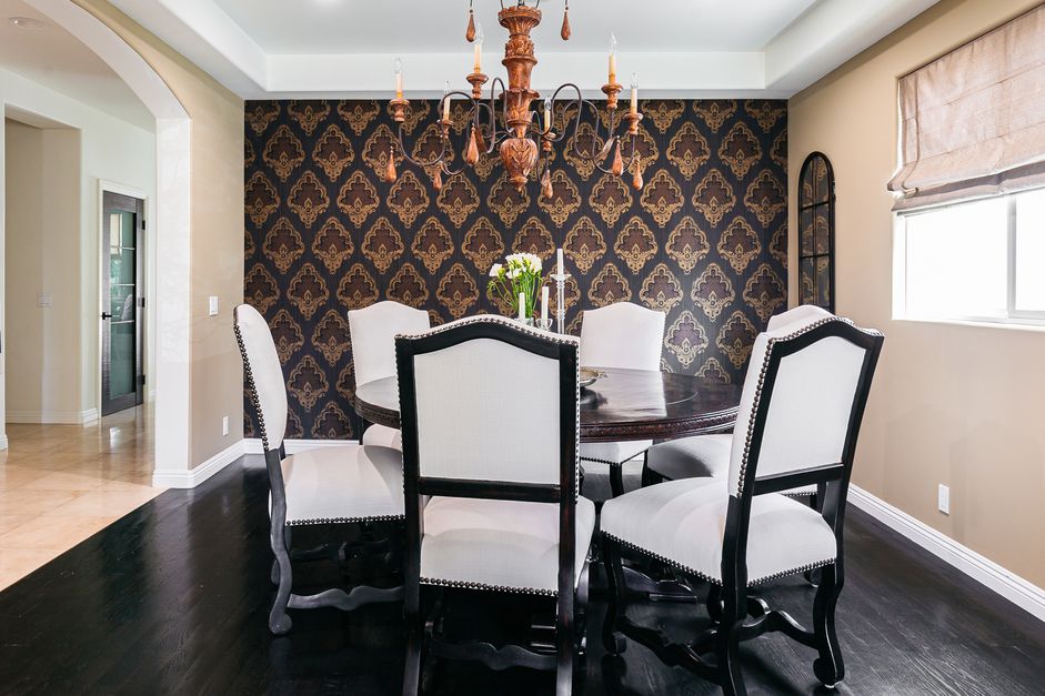 غرفة طعام أنيقة مع ورق حائط منقوش باللونين الأسود والبني خلف الكراسي البيضاء والسوداء