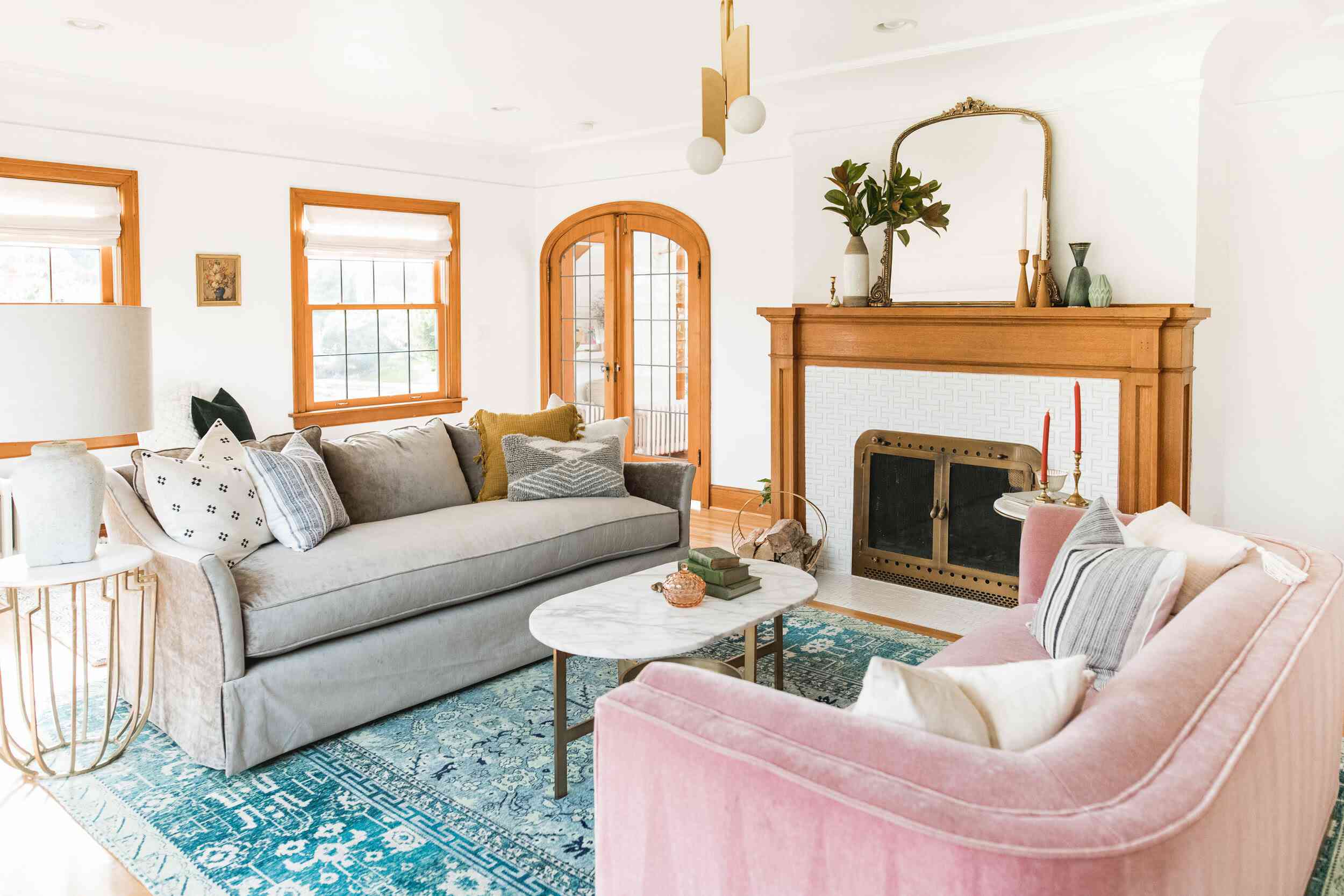 أريكة رمادية ووردية تواجه بعضهما البعض في غرفة المعيشة مع مدفأة