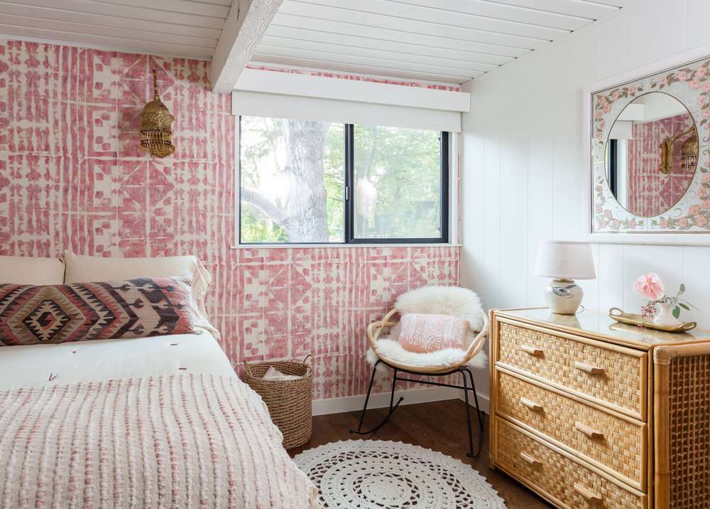 غرفة نوم في سن المراهقة مع جدار وردي مزخرف بورق الجدران.