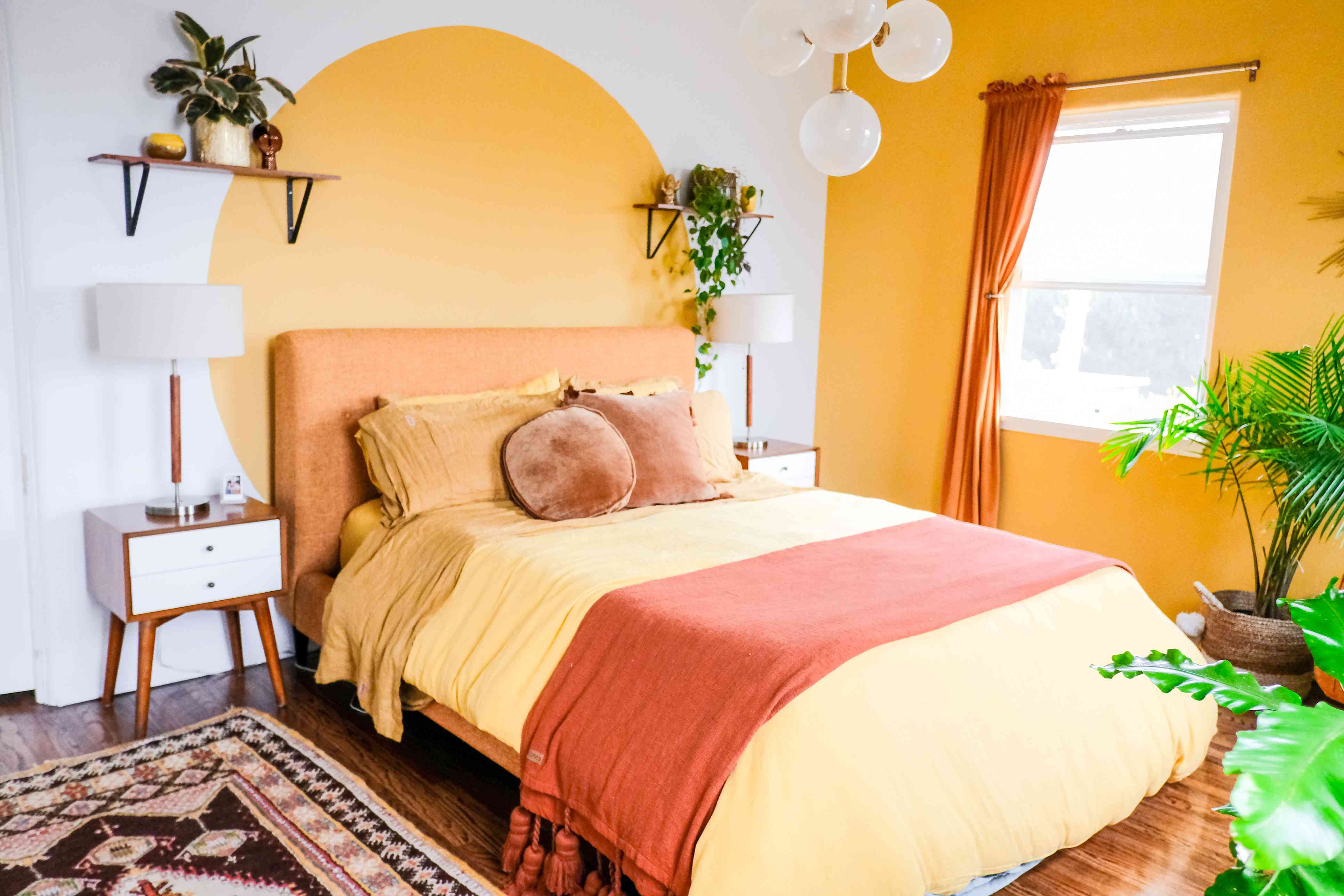 غرفة نوم بجدار أصفر لامع ولون محجوب بدائرة صفراء خلف السرير.