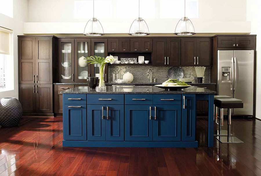 مطبخ حديث مع جزيرة زرقاء كبيرة وأسطح من الغرانيت ، وخزائن من الأرضية إلى السقف باللون البني الداكن ، وأجهزة من الفولاذ المقاوم للصدأ على أرضيات خشبية مصبوغة بالكرز.