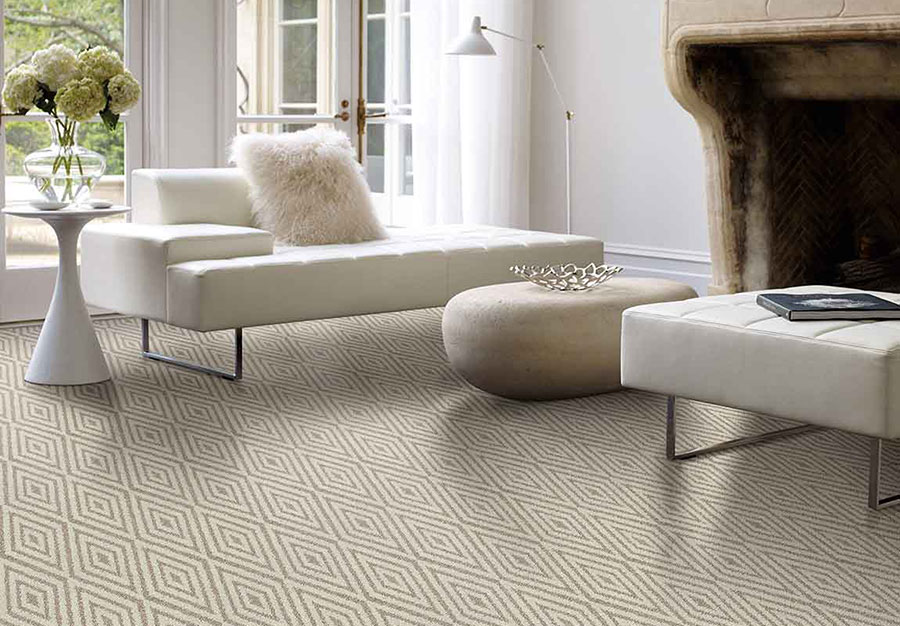 غرفة جلوس شيك مع أريكة بيضاء وعثمانية ومدفأة حجرية وطاولة على سجادة مزخرفة بالألماس.