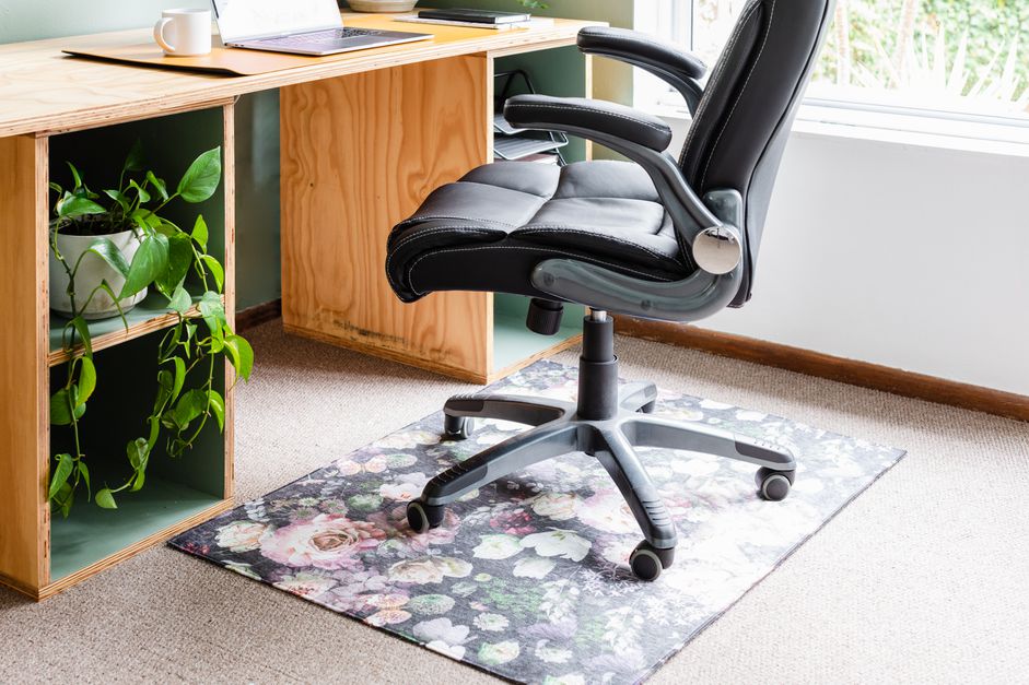 كرسي مكتب أعلى بساط كرسي أسود وزهور بالقرب من مكتب خشبي مقرّب